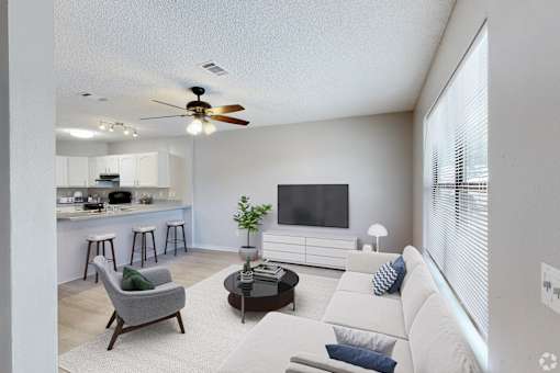 A living room with a grey armchair, a white sofa, and a black coffee table.
