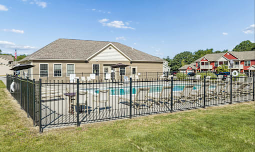 A house with a black fence and a pool in front.