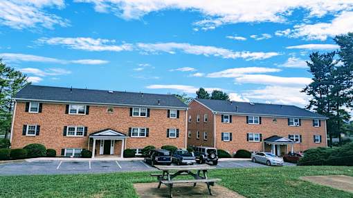 A red brick building with a parking lot in front.