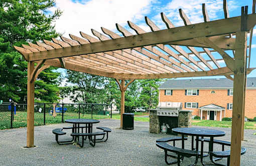 A wooden pergola with picnic tables underneath it.