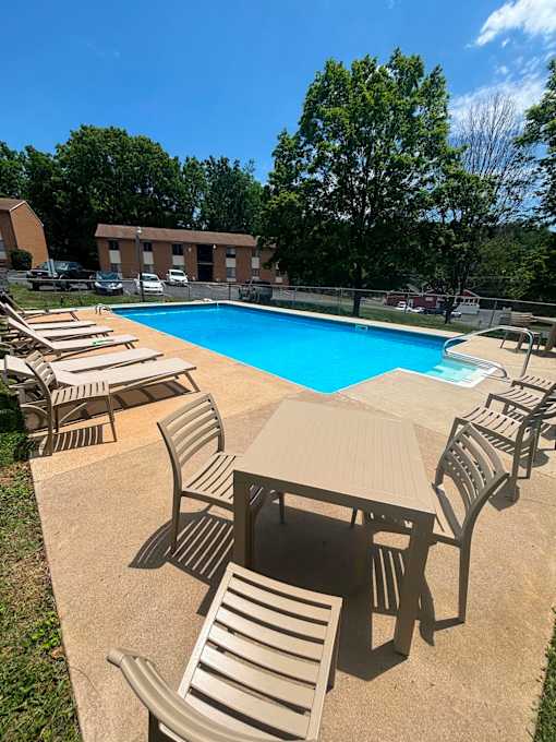 A pool surrounded by chairs and tables.