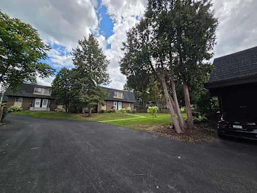 A black car is parked on a driveway in front of a house.