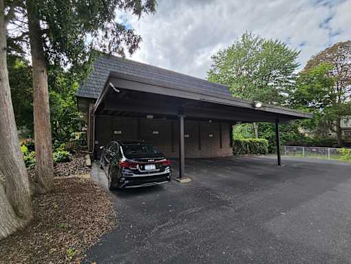 A black car is parked in front of a brown building.