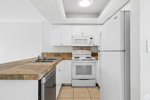 A kitchen with white cabinets and appliances.