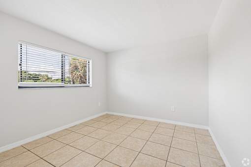 A room with a window and tiled floor.