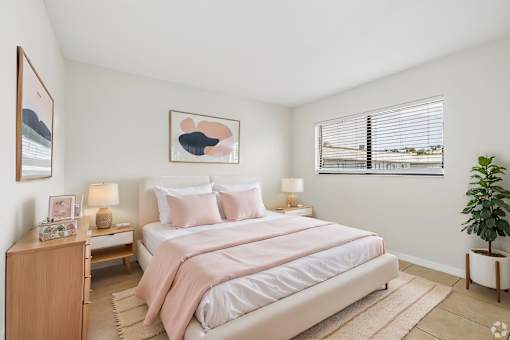 A bedroom with a large bed and a potted plant.