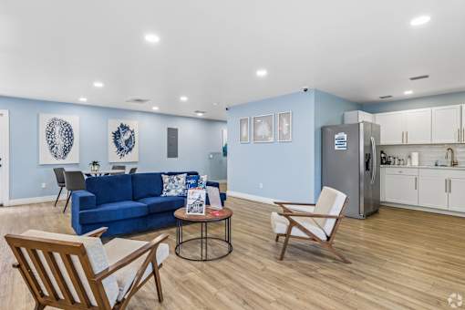 A blue couch sits in a living room with a kitchen in the background.
