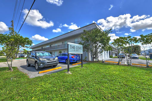 The Cove is a white building with a blue car parked in front.
