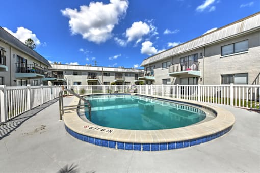 A swimming pool surrounded by a fence and buildings.