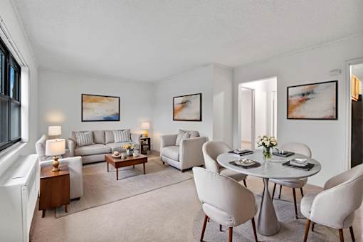 A living room with a grey couch, a coffee table, and a dining table set up.