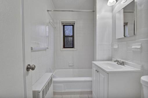 A white bathroom with a tub, sink, and mirror.