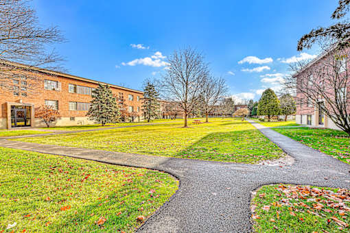 A pathway leads through a grassy area in front of a brick building.