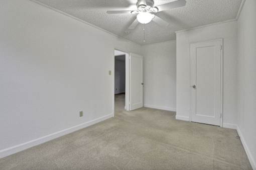 A room with a ceiling fan and carpeted floor.
