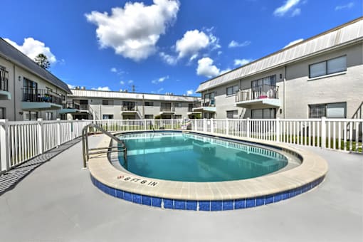 A swimming pool in a residential area with buildings in the background.