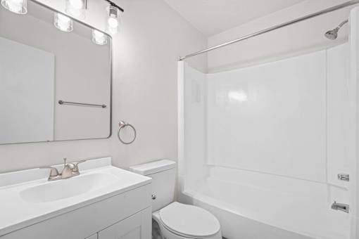 A white bathroom with a toilet, sink, and shower.
