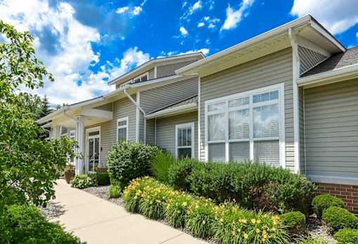 Building with bushes and a sidewalk at Encore Townhomes, Utica