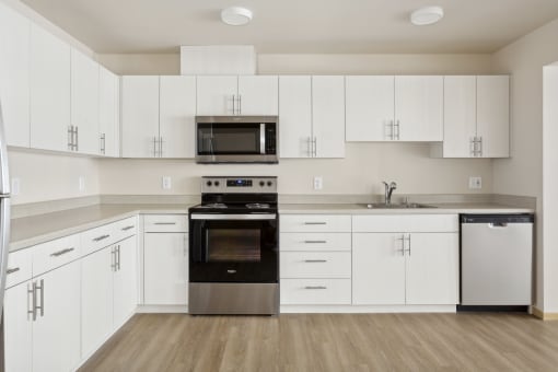 an empty kitchen with white cabinets and a stove and a microwave