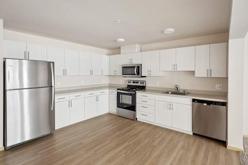 an empty kitchen with white cabinets and stainless steel appliances