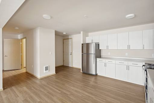 an empty kitchen with white cabinets and a stainless steel refrigerator
