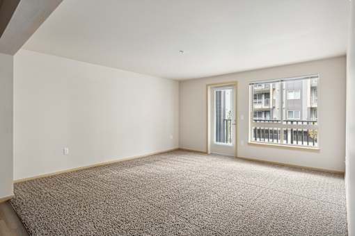 an empty living room with a large window and carpeting