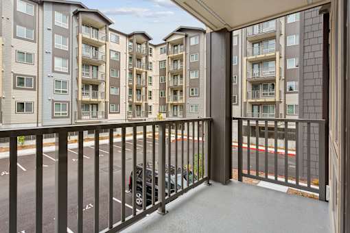 the view from the balcony of an apartment building with a black railing and a car
