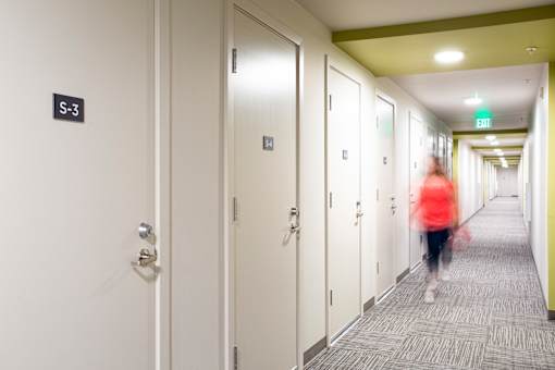 a woman walking down a hallway in a hotel room