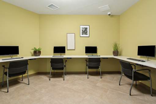 a computer lab with three desks and chairs and three monitors