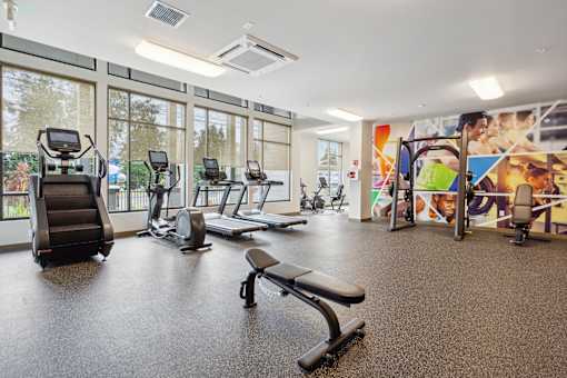a gym with treadmills and other exercise equipment in a building with large windows