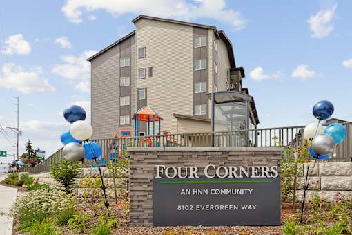 a sign that reads four corners an hin community with blue and white balloons on