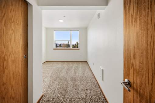A hallway with a carpeted floor and a door on the left.