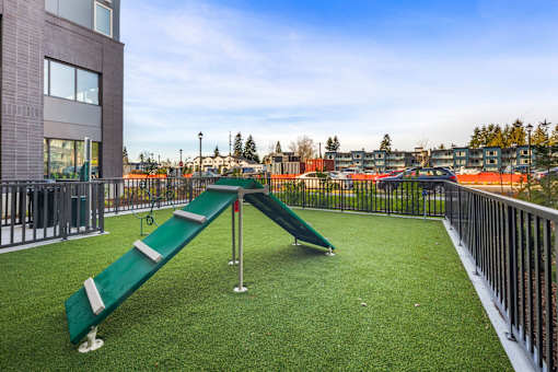 A playground with a green slide and a metal railing.