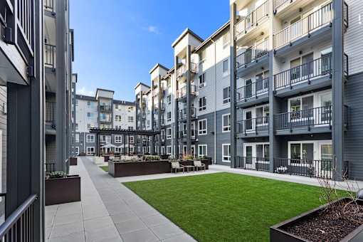 Apartment complex with a walkway and greenery in the foreground.