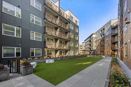 A long concrete walkway separates two buildings with balconies.