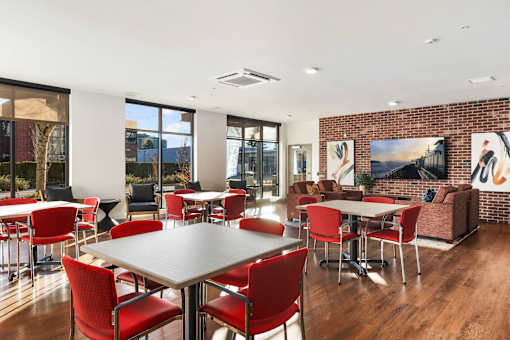 A room with a long table surrounded by red chairs.