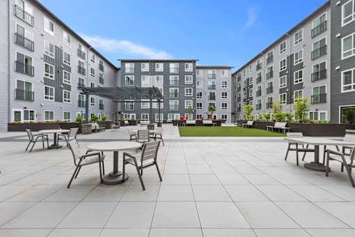 A courtyard with tables and chairs surrounded by apartment buildings.