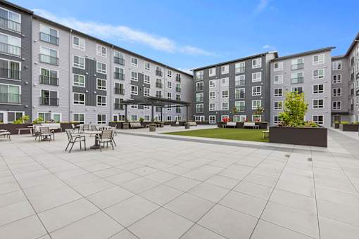 A large courtyard with a table and chairs surrounded by apartment buildings.