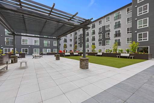 A large open patio area with a stone bench and a stone pillar in the middle.