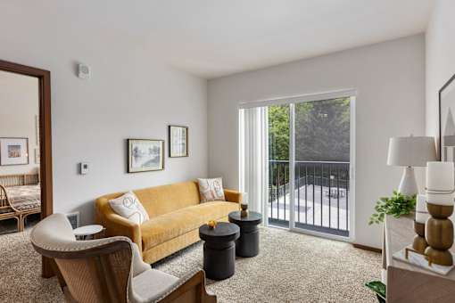 A living room with a yellow couch and a chair.