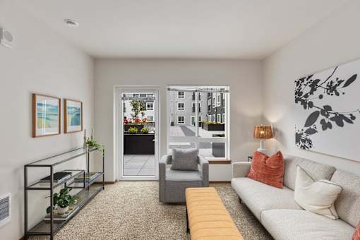 A living room with a white couch, a grey armchair, and a yellow bench.