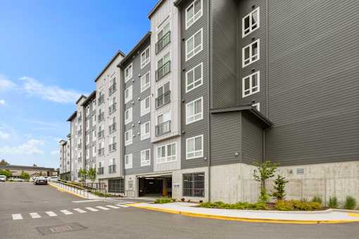 A large grey building with a parking lot in front.