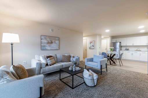 A living room with a grey couch, a black coffee table, and a painting on the wall.