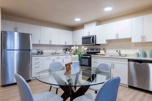 A modern kitchen with a glass table and chairs.