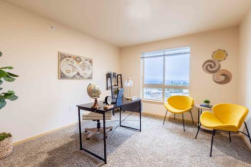 A room with a desk, chairs, and a window.