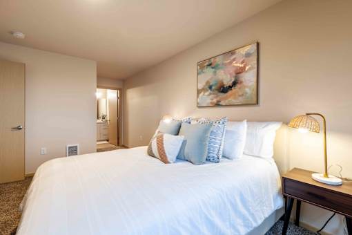 A bedroom with a large bed and a painting on the wall.