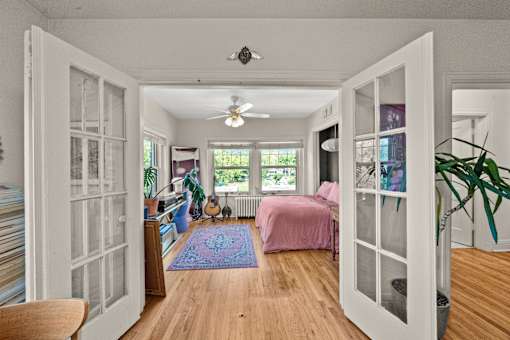 A room with a bed, a guitar, and a ceiling fan.