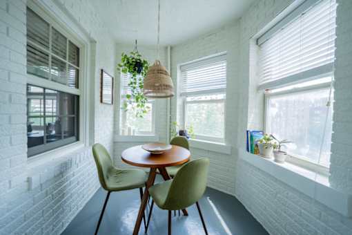 A white brick wall with a table and chairs in front of it.