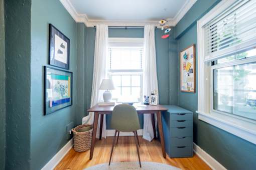 A room with a desk and chair in front of a window.