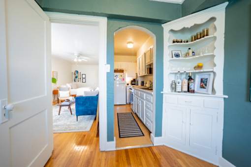 A kitchen with a blue wall and white cabinets.