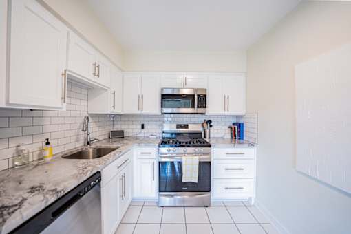 A kitchen with white cabinets and a black dishwasher.