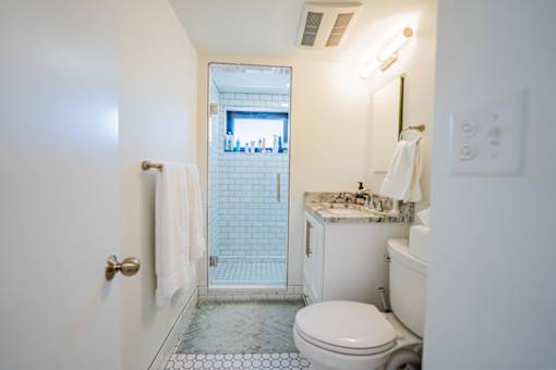 A white toilet with a marble top sits in a bathroom with a walk-in shower.